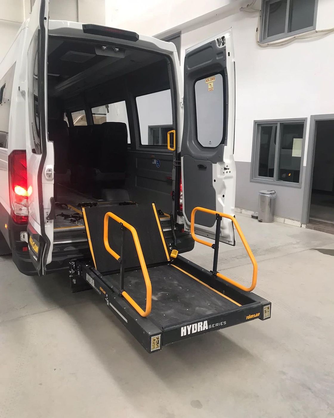Beyaz minibüsün arka kapısında sarı tutamaklı HYDRA serisi lift